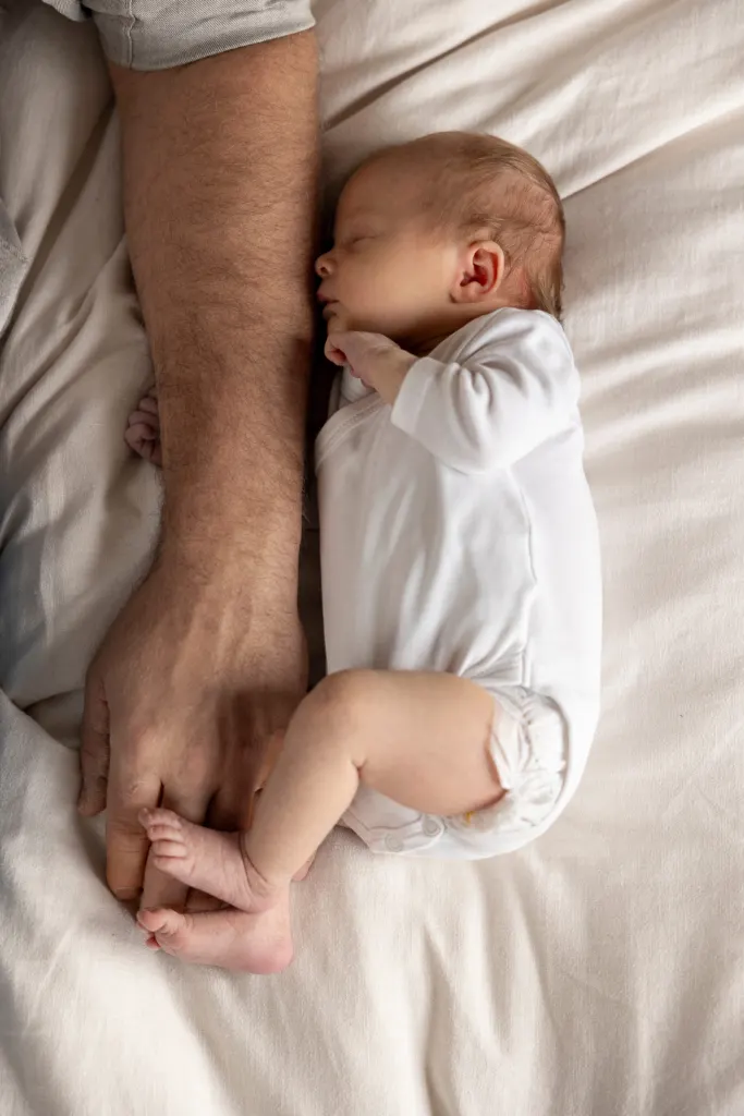 Pasgeboren baby slaapt naast de hand van een ouder