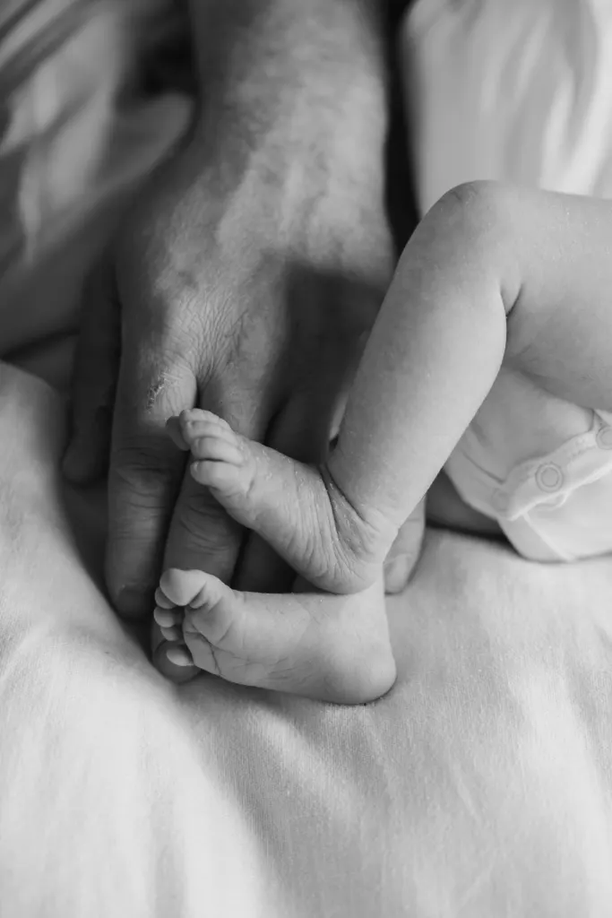 Zwart-witbeeld van babyvoetjes in de hand van een ouder