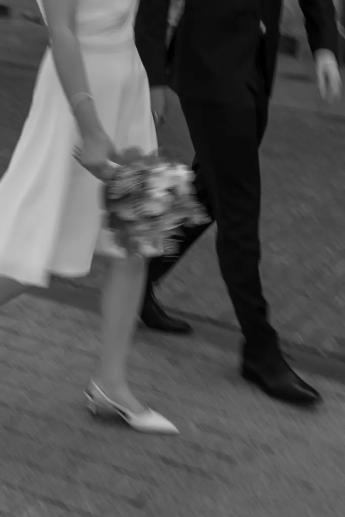 Bruidspaar wandelt hand in hand, de bruid met een boeket in de hand
