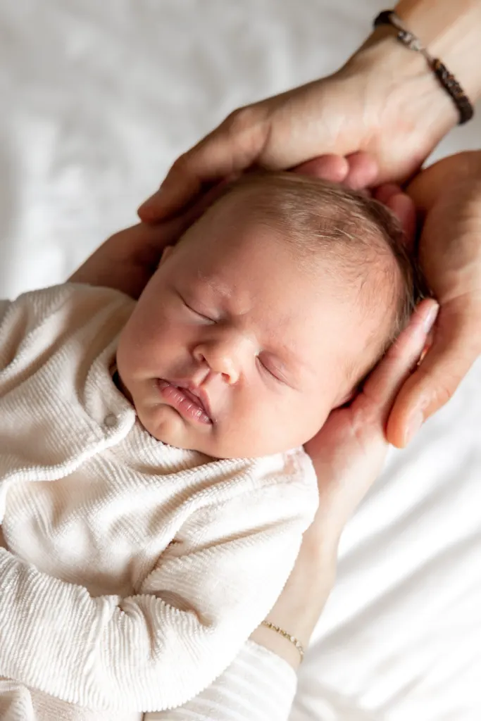 Slapende newborn, gedragen door de handen van een ouder
