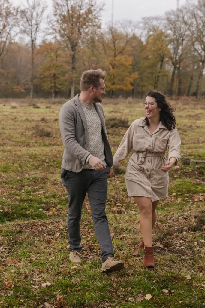 Koppel wandelt hand in hand door een herfstig landschap