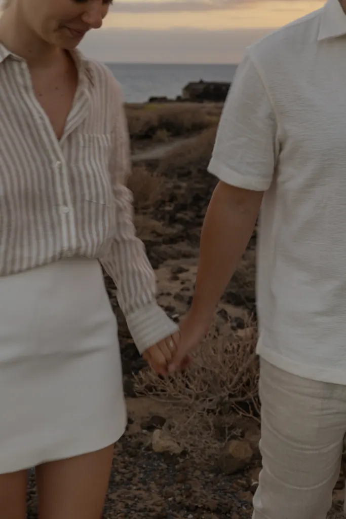 Koppel hand in hand op een kustpad bij zonsondergang