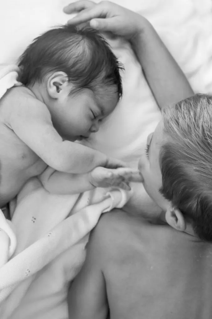 Zwart-witbeeld van een newborn met broer of zus op bed