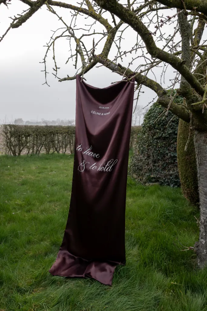 Bordeaux welkomstdoek dat aan een boom hangt in een weide