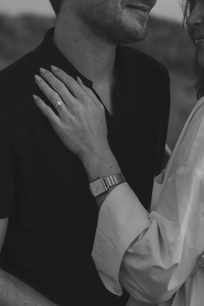 Zwart-witbeeld van een hand met verlovingsring op de borst van de partner