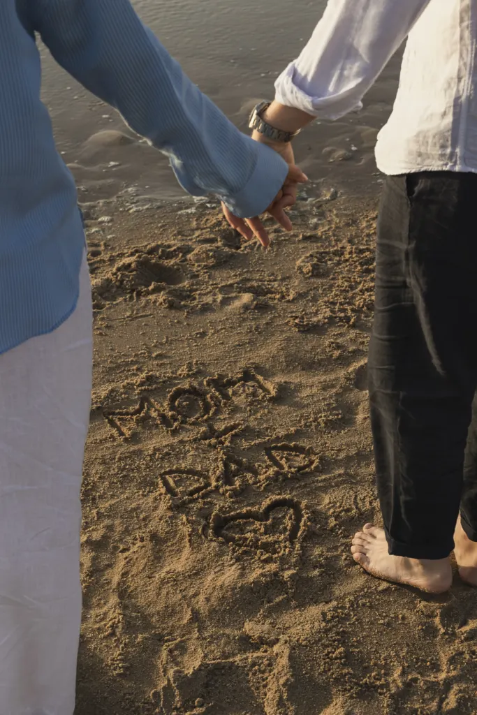 Mom + Dad met een hartje in het zand geschreven tijdens een zwangerschapsshoot aan zee